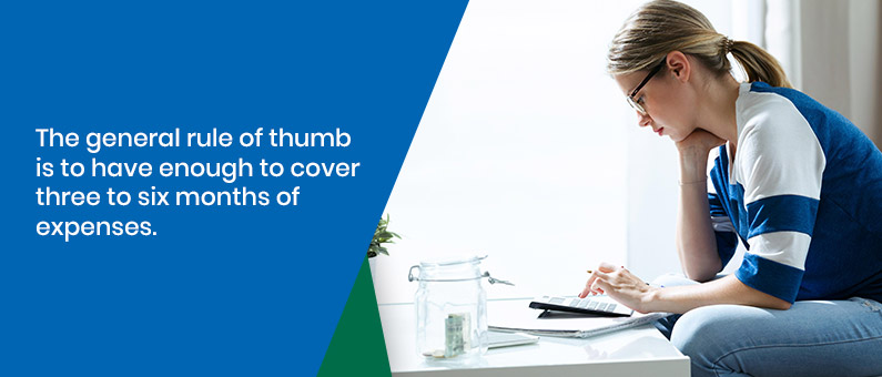 The general rule of thumb is to have enough to cover three to six months of expenses - woman with a calculator